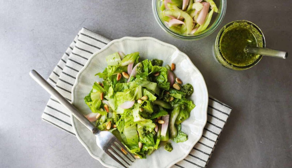 Masa üzerinde sos ve yeşil salata bulunmakta. Salata tabağının altında çizgili bir örtü bulunmakta.