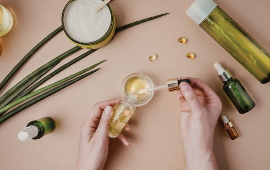 bir uzman krem hazırlıyor. masada krem, tonik ve serumlar bulunmakta.