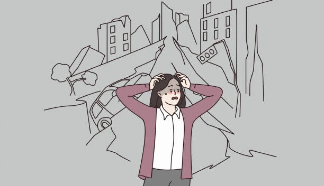 Çizim. Bir kadın panik halde ellerini saçlarına götürerek etrafına bakmakta. Yüzünde endişeli bir ifade bulunmakta. Arka tarafta ise binalar, asfalt deprem nedeniyle yıkılmış gözükmekte.