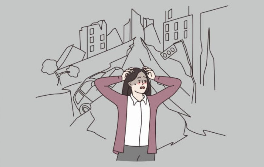 Çizim. Bir kadın panik halde ellerini saçlarına götürerek etrafına bakmakta. Yüzünde endişeli bir ifade bulunmakta. Arka tarafta ise binalar, asfalt deprem nedeniyle yıkılmış gözükmekte.