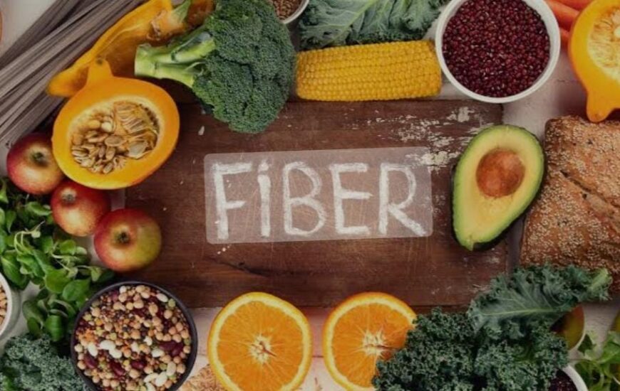 Ahşap bir masada fiber (lif) yazmakta. Etrafında ise meyve, sebze, yeşillik, bakliyat ve ekmek bulunmakta.